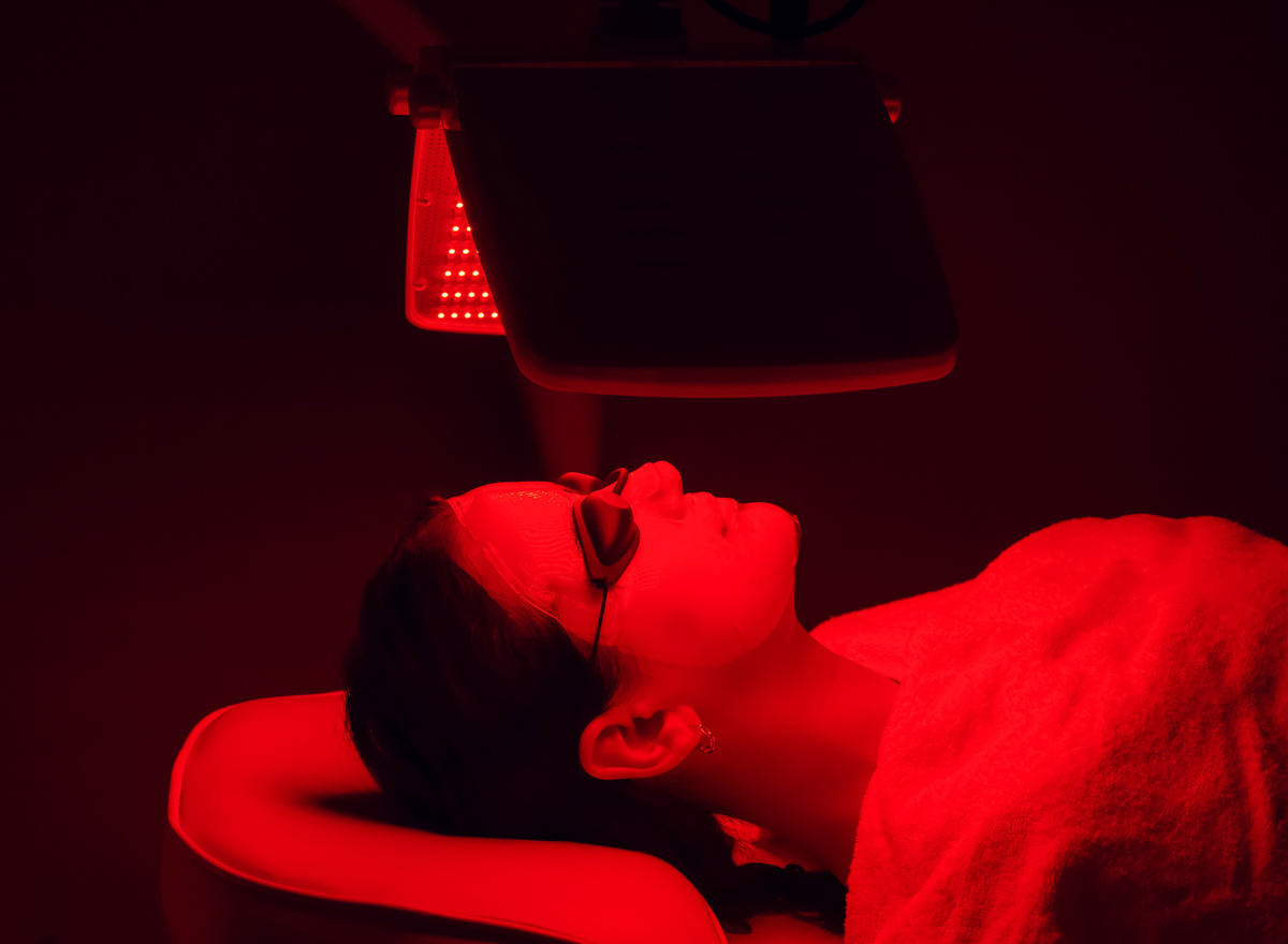 Young woman having red LED light facial therapy treatment in beauty salon. Beauty and wellness